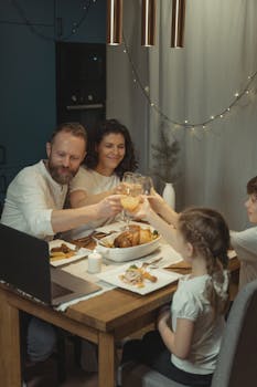 A family shares a festive Christmas dinner with a virtual toast, connecting online.