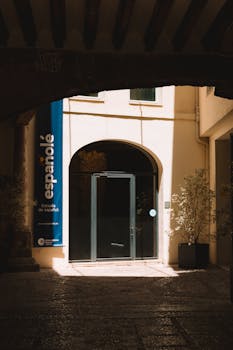 Arched entrance to a Spanish language school in Valencia, Spain, bathed in sunlight.